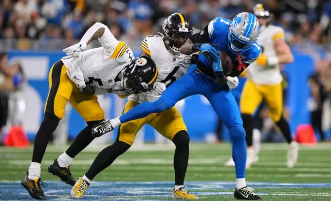Detroit Lions' Jameson Williams (1) is tackled by Pittsburgh Steelers' Patrick Queen (6) and Jalen Ramsey (5) during the second half of an NFL football game, Sunday, Dec. 21, 2025, in Detroit. (AP Photo/Ryan Sun)