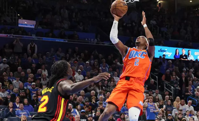 Oklahoma City Thunder guard Shai Gilgeous-Alexander, right, looks to shoot near Atlanta Hawks guard Keaton Wallace, left, during the second half of an NBA basketball game Monday, Dec. 29, 2025, in Oklahoma City. (AP Photo/Nate Billings)