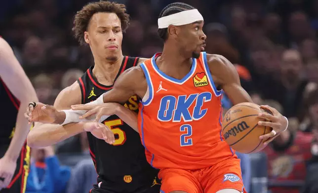 Oklahoma City Thunder guard Shai Gilgeous-Alexander (2) spins away from Atlanta Hawks guard Dyson Daniels, left, during the first half of an NBA basketball game Monday, Dec. 29, 2025, in Oklahoma City. (AP Photo/Nate Billings)