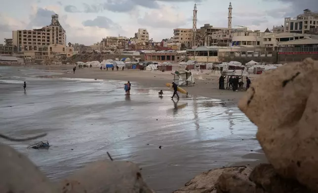 A Palestinian surfer carries his board into the sea along the shoreline in Gaza City, Sunday, Dec. 28, 2025. (AP Photo/Jehad Alshrafi)