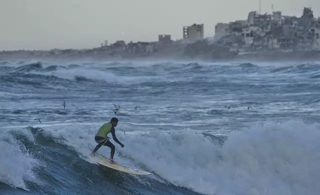 Palestinian Khalil Abu Jayyab surfs on the beach of Gaza City, Sunday, Dec. 28, 2025. (AP Photo/Jehad Alshrafi)
