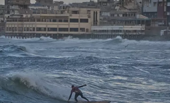 Palestinian Tahseen Abu Assi surfs on the beach of Gaza City, Sunday, Dec. 28, 2025. (AP Photo/Jehad Alshrafi)