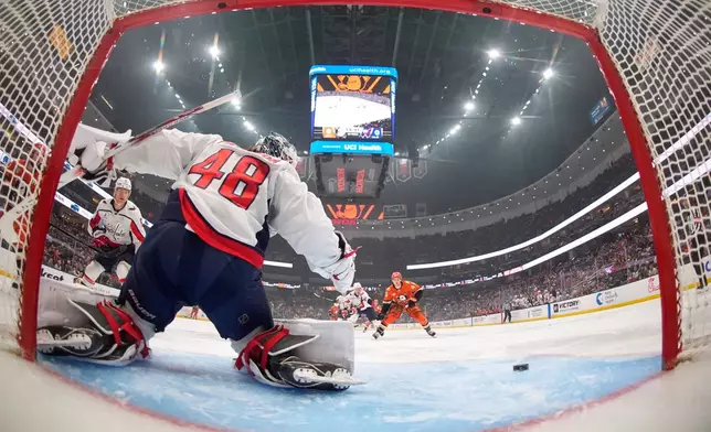 Washington Capitals goaltender Logan Thompson, left, deflects a shot as Anaheim Ducks right wing Beckett Sennecke, right, watches during the first period of an NHL hockey game Friday, Dec. 5, 2025, in Anaheim, Calif. (AP Photo/Mark J. Terrill)