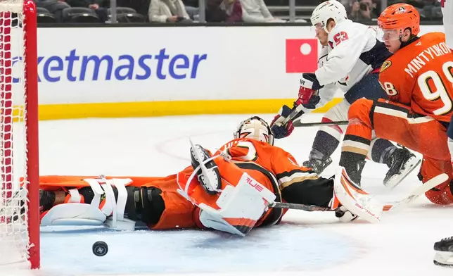 Washington Capitals center Ethen Frank, center, scores on Anaheim Ducks goaltender Ville Husso, left, as defenseman Pavel Mintyukov watches during the second period of an NHL hockey game Friday, Dec. 5, 2025, in Anaheim, Calif. (AP Photo/Mark J. Terrill)