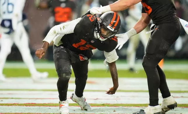 Cleveland Browns quarterback Shedeur Sanders (12) gets help from a teammate after scoring a touchdown on a run in the second half of an NFL football game against the Tennessee Titans in Cleveland, Sunday, Dec. 7, 2025. (AP Photo/Sue Ogrocki)