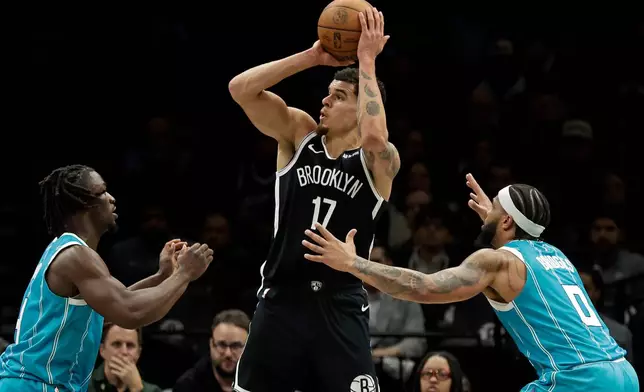 Brooklyn Nets forward Michael Porter Jr. (17) looks to shoot between Charlotte Hornets guard Sion James, left, and forward Miles Bridges (0) during the second half of an NBA basketball game Monday, Dec. 1, 2025, in New York. (AP Photo/Adam Hunger)