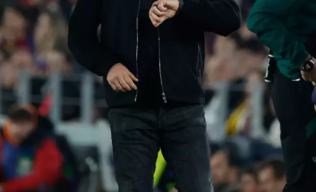 Barcelona's head coach Hansi Flick looks on his watch after the end of the Champions League opening phase soccer match between Barcelona and Eintracht Frankfurt in Barcelona, Spain, Tuesday, Dec. 9, 2025. (AP Photo/Joan Monfort)