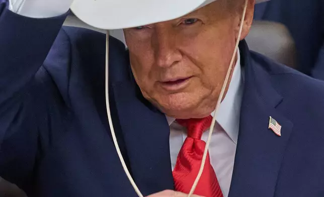 FILE - President Donald Trump tries on a hat gifted to him from members of the 1980 U.S. Men's Olympic Hockey team Friday, Dec. 12, 2025, in the Oval Office of the White House in Washington. (AP Photo/Jacquelyn Martin, File)