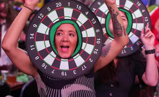 FILE - Dart fans watch the World Darts Championships, at Alexandra Palace in London, Friday, Dec. 12, 2025. (AP Photo/Kin Cheung, File)