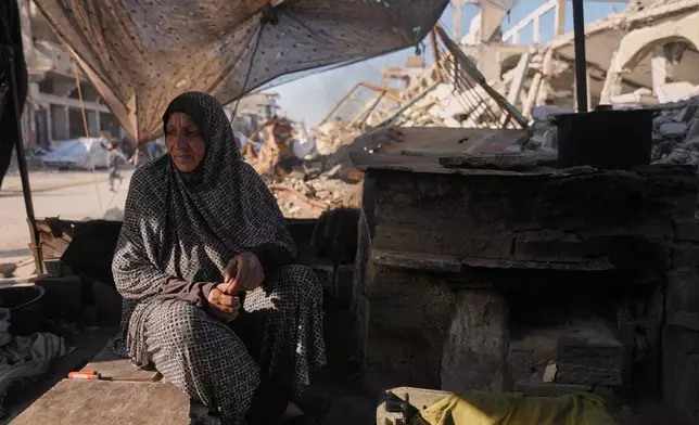Amal Matar, 65, sits next to the oven as she cooks for her family in the Al-Shati camp, northern Gaza Strip, Thursday, Dec. 25, 2025. (AP Photo/Jehad Alshrafi)