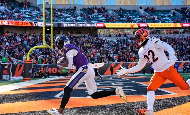 Baltimore Ravens wide receiver Zay Flowers, left, makes a catch for a touchdown past Cincinnati Bengals safety Geno Stone (22) during the first half of an NFL football game, Sunday, Dec. 14, 2025, in Cincinnati. (AP Photo/Carolyn Kaster)