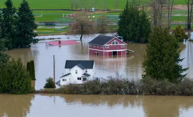A n aerial view of a home and a barn surrounded by floodwaters in Snohomish, Wash., Thursday, Dec. 11, 2025. (AP Photo/Stephen Brashear)