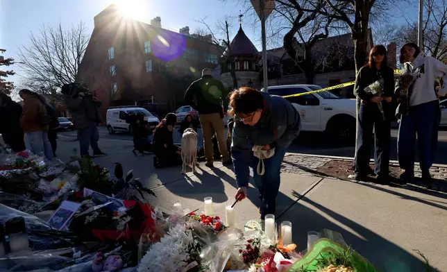 A woman lights a candle at a memorial set up in front of the Barus and Holley engineering building at Brown University in Providence, RI, Thursday, Dec. 18, 2025. (AP Photo/ Mark Stockwell)
