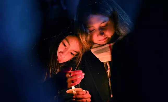FILE - People hold candles during a vigil in Providence, R.I., for those injured or killed in the previous day's shooting on the campus of Brown University, Sunday, Dec. 14, 2025. (AP Photo/Steven Senne, File)