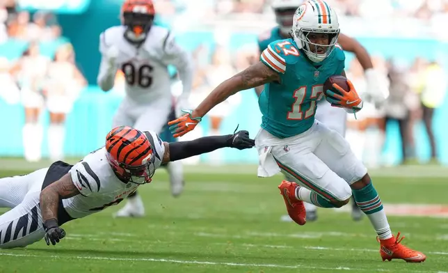 Miami Dolphins wide receiver Jaylen Waddle (17) evades a tackle by Cincinnati Bengals safety Geno Stone (22) during the first half of an NFL football game, Sunday, Dec. 21, 2025, in Miami Gardens, Fla. (AP Photo/Rebecca Blackwell)