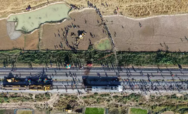 An excavator dig a pit to burry the carcass an Asiatic wild elephant being removed from a railway track after a speeding train hit a heard of wild elephant in the early morning in Changjurai village east of Guwahati, India, Saturday, Dec. 20, 2025. (AP Photo/Anupam Nath)