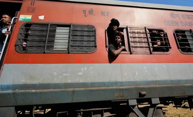 Passengers from a train look at a carcass of an Asiatic wild elephant (unseen) being removed from a railway track after a speeding train hit a heard of wild elephant in the early morning in Changjurai village east of Guwahati, India, Saturday, Dec. 20, 2025. (AP Photo/Anupam Nath)