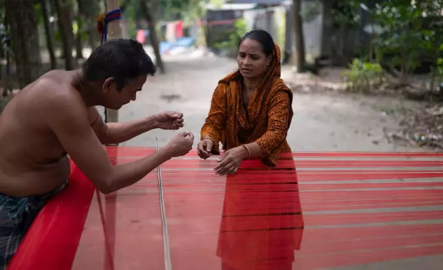 Handloom weavers arrange threads at a weaving workshop in Tangail District, Bangladesh, Nov. 5, 2025. (AP Photo/Mahmud Hossain Opu)