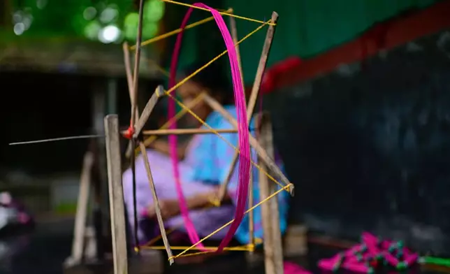 A weaver uses a spinning wheel to make yarn to be used in the making of Tangail sarees at a workshop in Tangail District, Bangladesh, Nov. 5, 2025. (AP Photo/Mahmud Hossain Opu)