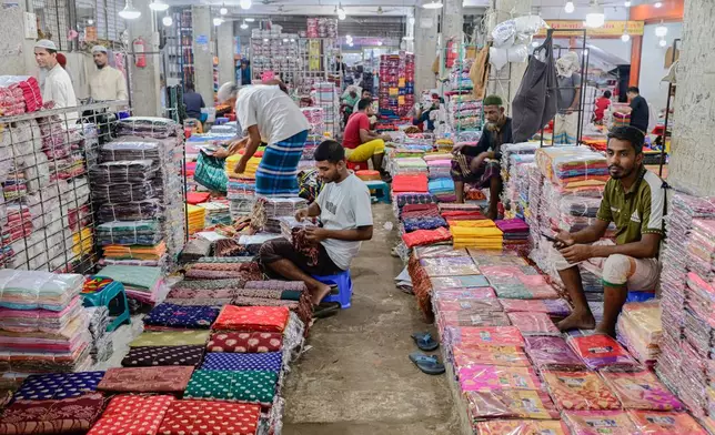 Shopkeepers arrange saris at a weekly wholesale market in Tangail District, Bangladesh, Nov. 5, 2025. (AP Photo/Mahmud Hossain Opu)