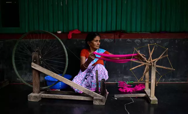 A weaver uses a spinning wheel to make yarn to be used in the making of Tangail sarees at a workshop in Tangail District, Bangladesh, Nov. 5, 2025. (AP Photo/Mahmud Hossain Opu)
