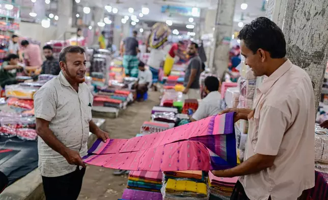 A customer examines a Tangail sari at a weekly wholesale market in Tangail District, Bangladesh, Nov. 5, 2025. (AP Photo/Mahmud Hossain Opu)