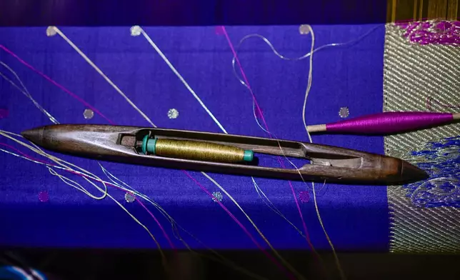 A shuttle holding the weft thread is seen on a hand-operated loom, which is used to create the renowned Tangail sarees at a traditional weaving workshop in Tangail District, Bangladesh, Nov. 5, 2025. (AP Photo/Mahmud Hossain Opu)