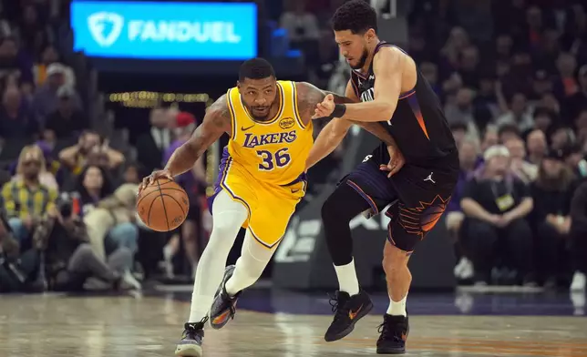 Los Angeles Lakers guard Marcus Smart (36) drives past Phoenix Suns guard Devin Booker during the first half of an NBA basketball game, Tuesday, Dec. 23, 2025, in Phoenix. (AP Photo/Rick Scuteri)
