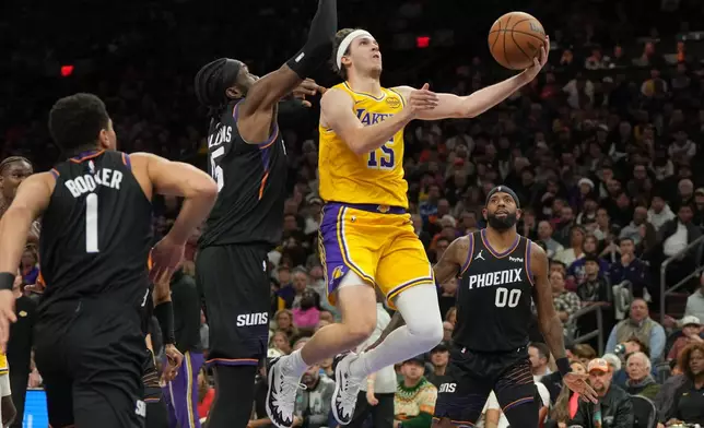 Los Angeles Lakers guard Austin Reaves drives between Phoenix Suns guard Devin Booker, center Mark Williams (15), and forward Royce O'Neale (00) during the first half of an NBA basketball game, Tuesday, Dec. 23, 2025, in Phoenix. (AP Photo/Rick Scuteri)