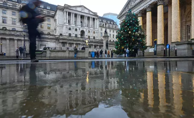 The Bank of England is reflected on a wet pavement in London, as the Monetary Policy Committee (MPC) will publish their decision on interest rates, Thursday, Dec. 18, 2025. (AP Photo/Kirsty Wigglesworth)