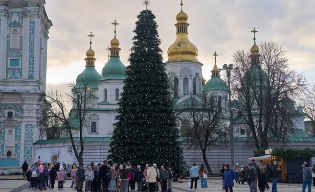 People walk around the Christmas tree in front of St. Sophia Monastery in central Kyiv, Ukraine, Wednesday, Dec. 10, 2025. (AP Photo/Efrem Lukatsky)