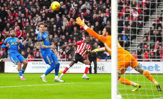Sunderland's Simon Adingra, center, scores their side's first goal of the game past Leeds United goalkeeper Lucas Perri during the English Premier League soccer match in Sunderland, England, Sunday, Dec. 28, 2025. (Owen Humphreys/PA via AP)