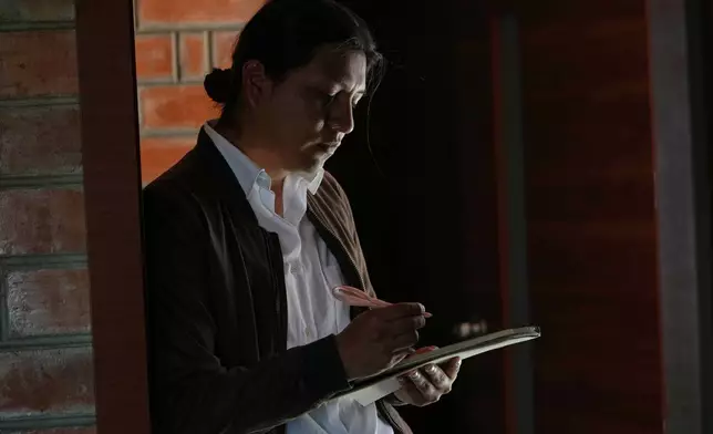 Yarik Sisa, an artist with Yay Animación, sketches in his notebook while his colleagues talk about their project "Aya Somos," the first Quichua animated short, blending Otavalo culture with Japanese-style anime, in Hatun Rumi, Ecuador, Wednesday, Dec. 3, 2025. (AP Photo/Dolores Ochoa)