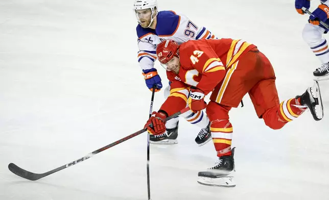 Edmonton Oilers' Connor McDavid (97) checks Calgary Flames' Adam Klapka during the third period of an NHL hockey game in Calgary, Alberta, Saturday, Dec. 27, 2025. (Jeff McIntosh/The Canadian Press via AP)