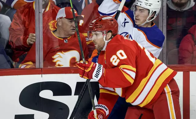 Edmonton Oilers' Ryan Nugent-Hopkins (93) is checked by Calgary Flames' Blake Coleman (20) during first-period NHL hockey game action in Calgary, Alberta, Saturday, Dec. 27, 2025. (Jeff McIntosh/The Canadian Press via AP)