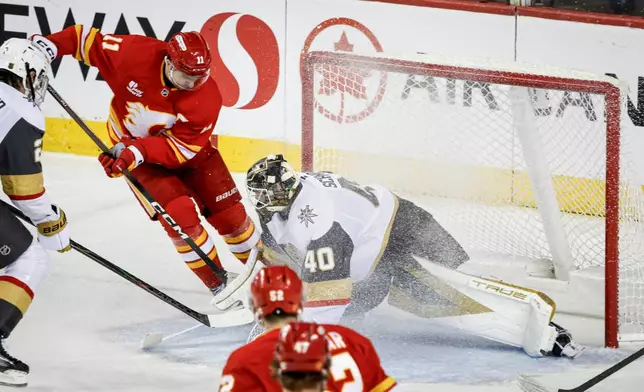 Vegas Golden Knights goalie Akira Schmid is scored on by Calgary Flames' Mikael Backlund during the second period of an NHL hockey game, in Calgary, Alberta, Saturday, Dec. 20, 2025. (Jeff McIntosh/The Canadian Press via AP)