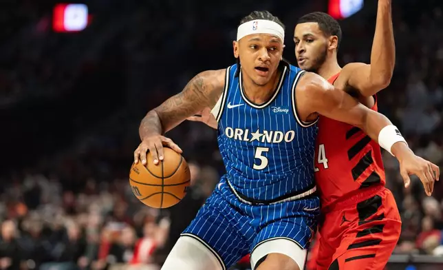 Orlando Magic forward Paolo Banchero, left, dribbles against the Portland Trail Blazers forward Kris Murray, right, during the first half of an NBA basketball game Tuesday Dec. 23, 2025, in Portland, Ore. (AP Photo/Howard Lao)