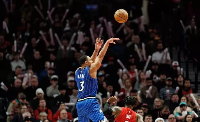 Orlando Magic guard Desmond Bane (3) shoots the ball against Portland Trail Blazers guard Caleb Love, right, during the second half of an NBA basketball game Tuesday Dec. 23, 2025, in Portland, Ore. (AP Photo/Howard Lao)