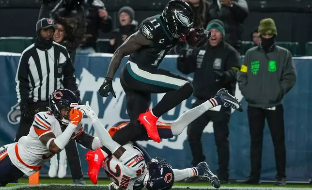 Philadelphia Eagles wide receiver A.J. Brown (11) jumps over Chicago Bears cornerback Nahshon Wright (26) to score a touchdown during the second half of an NFL football game, Friday, Nov. 28, 2025, in Philadelphia. (AP Photo/Matt Slocum)