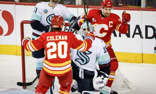 Seattle Kraken's Shane Wright, left, and goalie Joey Daccord react as Calgary Flames' Mikael Backlund, right, celebrates his goal with teammate Blake Coleman, centre, during the second period of an NHL hockey game, in Calgary, Alberta, Thursday, Dec. 18, 2025. (Jeff McIntosh/The Canadian Press via AP)