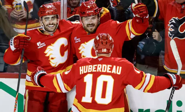 Calgary Flames' Matt Coronato, left, celebrates his goal with teammates Rasmus Andersson, center, and Jonathan Huberdeau during the third period of an NHL hockey game against the Seattle Kraken in Calgary, Alberta, Thursday, Dec. 18, 2025. (Jeff McIntosh/The Canadian Press via AP)