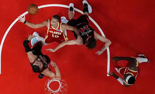 Atlanta Hawks forward Zaccharie Risacher (10) and Chicago Bulls forward Matas Buzelis (14) vie for a loose ball during the first half of an NBA basketball game, Tuesday, Dec. 23, 2025, in Atlanta. (AP Photo/Mike Stewart)