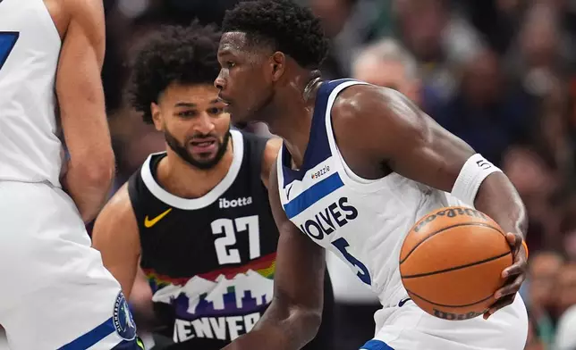 Minnesota Timberwolves guard Anthony Edwards, front, drives past Denver Nuggets guard Jamal Murray in the first half of an NBA basketball game, Thursday, Dec. 25, 2025, in Denver. (AP Photo/David Zalubowski)
