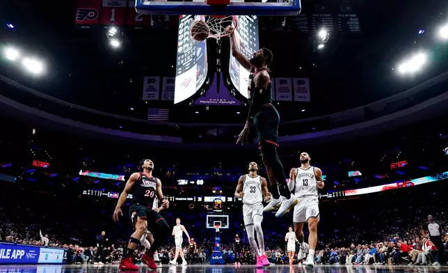 Philadelphia 76ers' Paul George, second from right, dunks the ball during the first half of an NBA basketball game against the Brooklyn Nets, Tuesday, Dec. 23, 2025, in Philadelphia. (AP Photo/Chris Szagola)