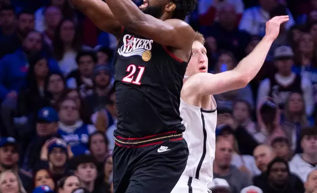 Philadelphia 76ers' Joel Embiid, left, goes up for the shot against Brooklyn Nets' Danny Wolf, right, during the first half of an NBA basketball game, Tuesday, Dec. 23, 2025, in Philadelphia. (AP Photo/Chris Szagola)
