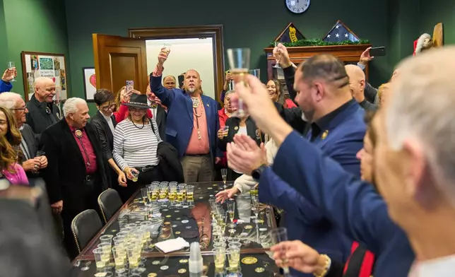 John Lowery, N.C. State Rep. and Chairman of the Lumbee Tribe of N.C., leads a toast to Sen. Thom Tillis, R-N.C., center, front right, as members of the Lumbee Tribe of North Carolina, celebrate the passage of a bill granting their people federal recognition, on Capitol Hill, in Washington, Wednesday, Dec. 17, 2025. (AP Photo/Jacquelyn Martin)
