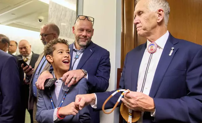 Austin Curt Thomas, 11, gets a celebratory fist bump from Sen. Thom Tillis, R-N.C., as he and his father Aaron Thomas, of Pembroke, N.C., join fellow members of the Lumbee Tribe of North Carolina, to celebrate after the passage of a bill granting their people federal recognition, on Capitol Hill, in Washington, Wednesday, Dec. 17, 2025. (AP Photo/Jacquelyn Martin)