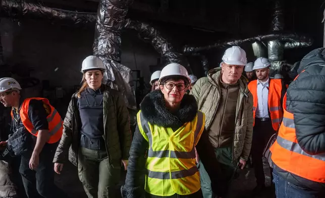 EU Commissioner for Enlargement Marta Kos, front, looks at a production hall damaged after a recent Russian missile attack at DTEK's power plant in Ukraine, on Wednesday, Dec. 10, 2025. (AP Photo/Evgeniy Maloletka)