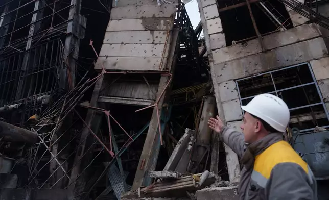 A worker shows damages of a production hall after a recent Russian missile attack at DTEK's power plant in Ukraine, on Wednesday, Dec. 10, 2025. (AP Photo/Evgeniy Maloletka)