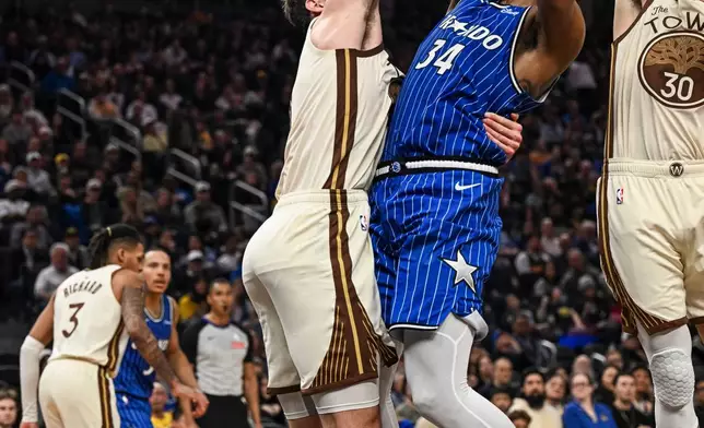 Orlando Magic center Wendell Carter Jr. (34) is fouled by Golden State Warriors center Quinten Post, center left, during the first half of an NBA basketball game, Monday, Dec. 22, 2025, in San Francisco (AP Photo/Justine Willard)